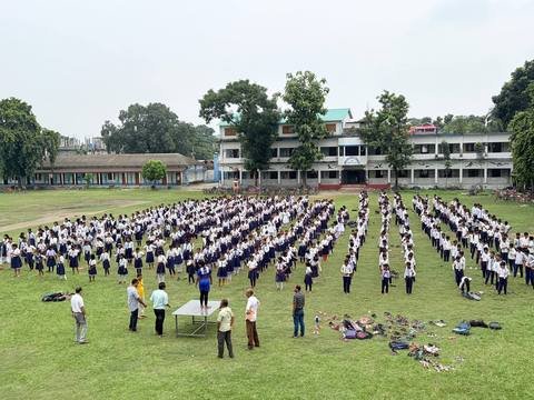 Hundreds of students in white and navy uniform doing a mass drill on the field