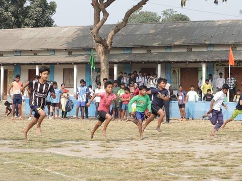 Boys running a sprint race barefoot across the school field